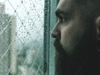 man looking out window afraid